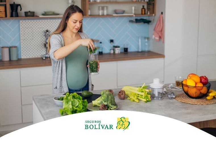 Mujer embarazada preparando un batido verde con vegetales para prevenir la anemia.