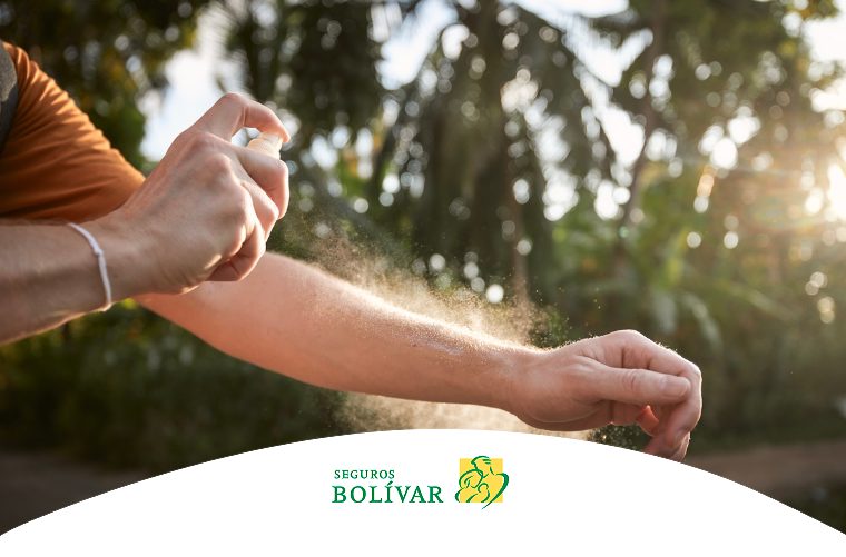 Una persona aplicándose repelente de insectos en aerosol en el brazo, en un entorno natural al aire libre con vegetación de fondo.
