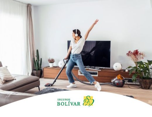 Mujer con audífonos bailando mientras aspira la sala, representando el bienestar de un hogar limpio.
