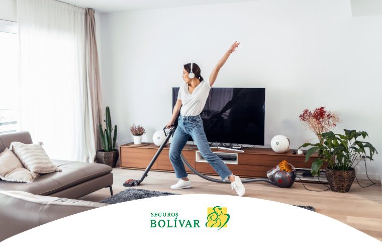 Mujer con audífonos bailando mientras aspira la sala, representando el bienestar de un hogar limpio.