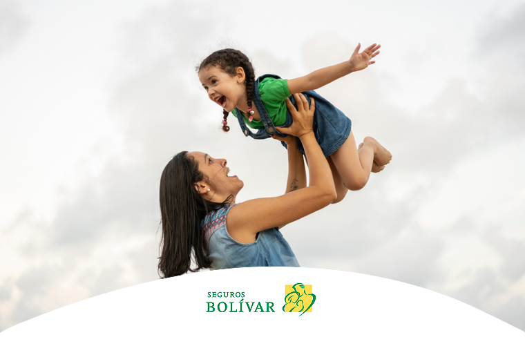 Madre alzando a su pequeña hija, ambas riendo y disfrutando de un momento de juego al aire libre.